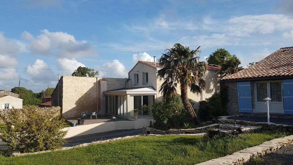 une maison avec un palmier dans la cour dans l'établissement La Frouardière, 3 gîtes de charme, à Antigny