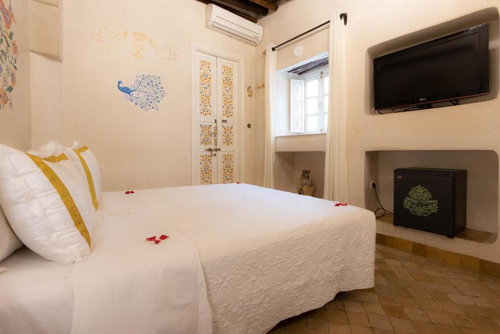une chambre avec un lit blanc et une télévision à écran plat dans l'établissement Riad Palais Des Princesses & Spa, à Marrakech