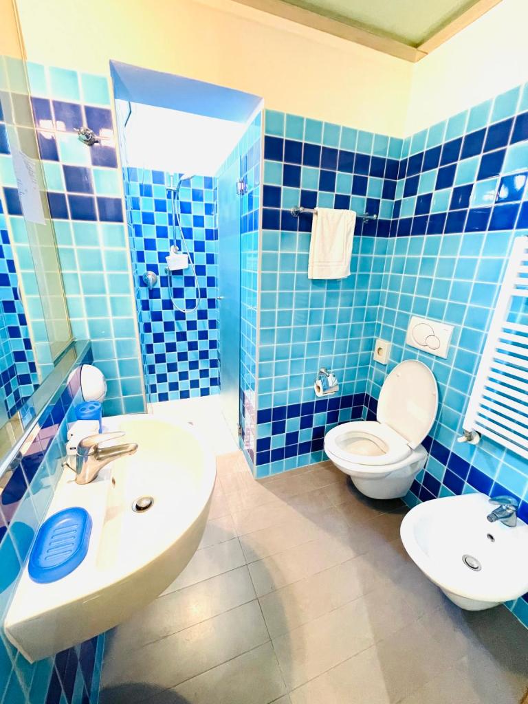 La salle de bains est pourvue de carrelage bleu, d'un lavabo et de toilettes. dans l'établissement Hotel Vannucci, à Rimini