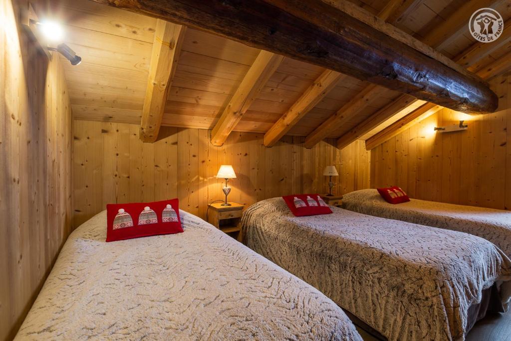 deux lits dans une chambre aux murs en bois dans l'établissement Chalet 13 personnes-Le Vanvolet, aux Saisies