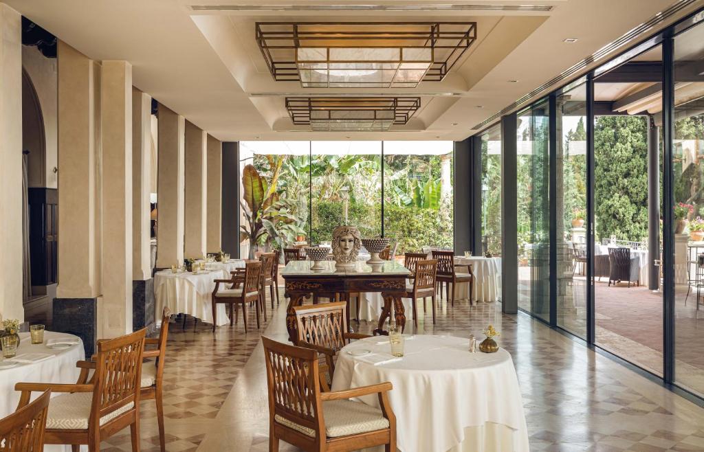 une salle à manger avec tables, chaises et fenêtres dans l'établissement Grand Hotel Timeo, A Belmond Hotel, Taormina, à Taormine