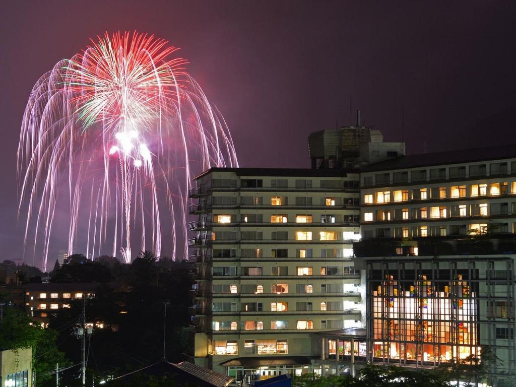 un feu d'artifice devant un bâtiment la nuit dans l'établissement Kinugawa Plaza Hotel, à Nikkō