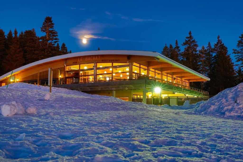 un grand bâtiment dans la neige la nuit dans l'établissement Chaleureux appartement aux pieds des pistes, à Chamrousse