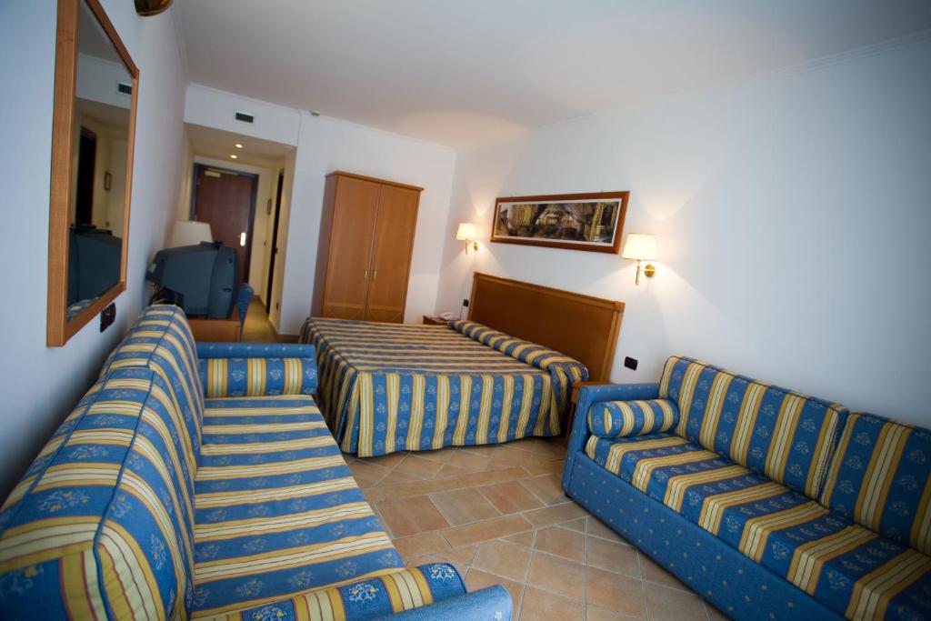 une chambre d'hôtel avec deux canapés et une télévision dans l'établissement Palace Hotel San Michele, à Monte SantʼAngelo
