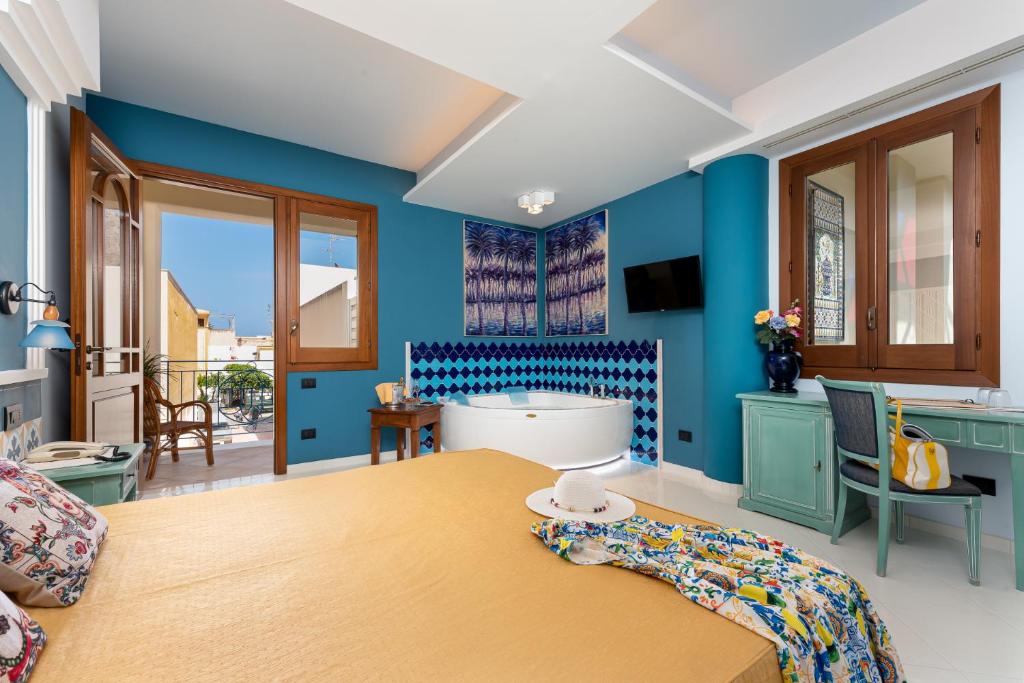 - une chambre avec des murs bleus et une baignoire dans l'établissement Hotel Sicilya, à San Vito Lo Capo