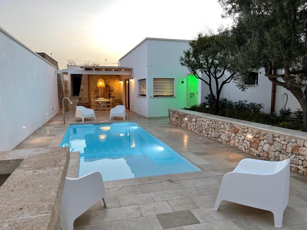 - une piscine dans un jardin avec des chaises blanches et une table dans l'établissement Le Liame Antico Trullo, à Gagliano del Capo