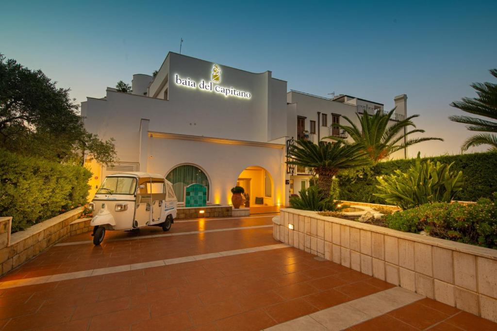 une vieille voiture garée devant un immeuble dans l'établissement Hotel Baia Del Capitano, à Cefalù