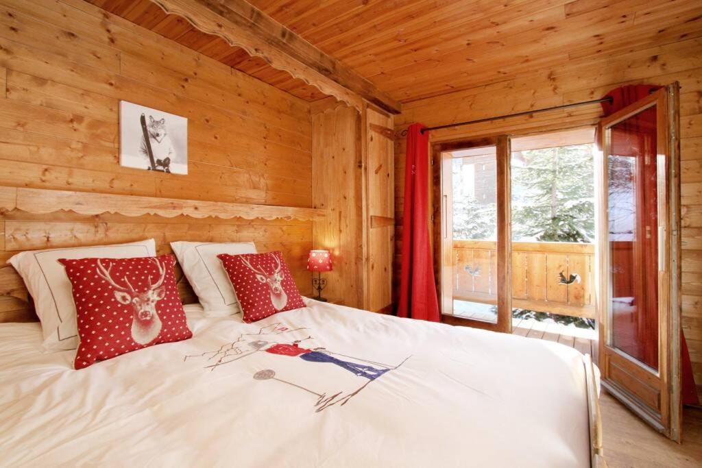 une chambre avec un lit avec des oreillers rouges dessus dans l'établissement 2AlpesChalets - Chalet Marie 1 - Standing et Sauna au pieds des pistes, à Les Deux Alpes
