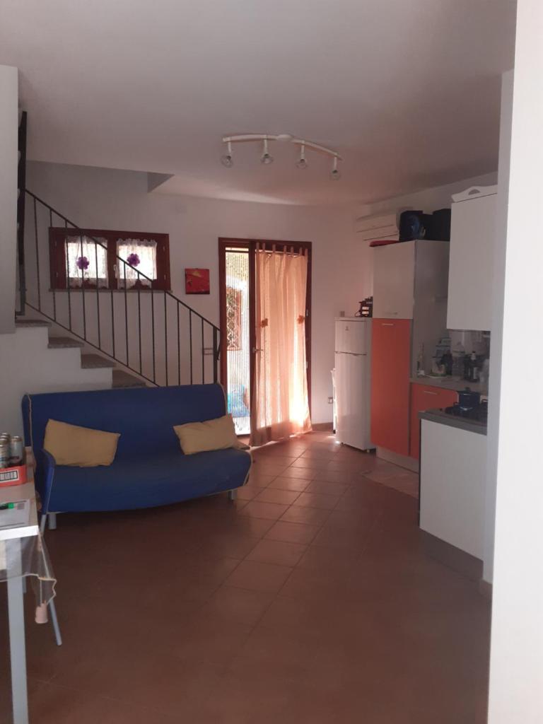 un salon avec un canapé bleu et une cuisine dans l'établissement Villa su due livelli super accessoriata, à SantʼAnna Arresi