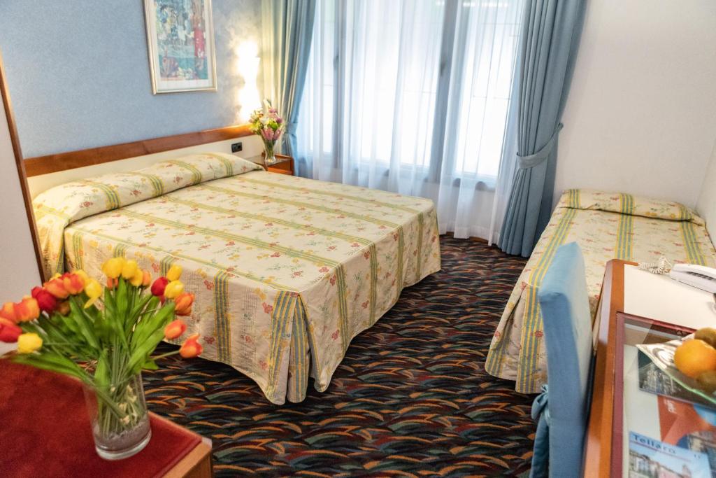 une chambre d'hôtel avec deux lits et un vase de fleurs dans l'établissement Hotel San Terenzo, à Lerici