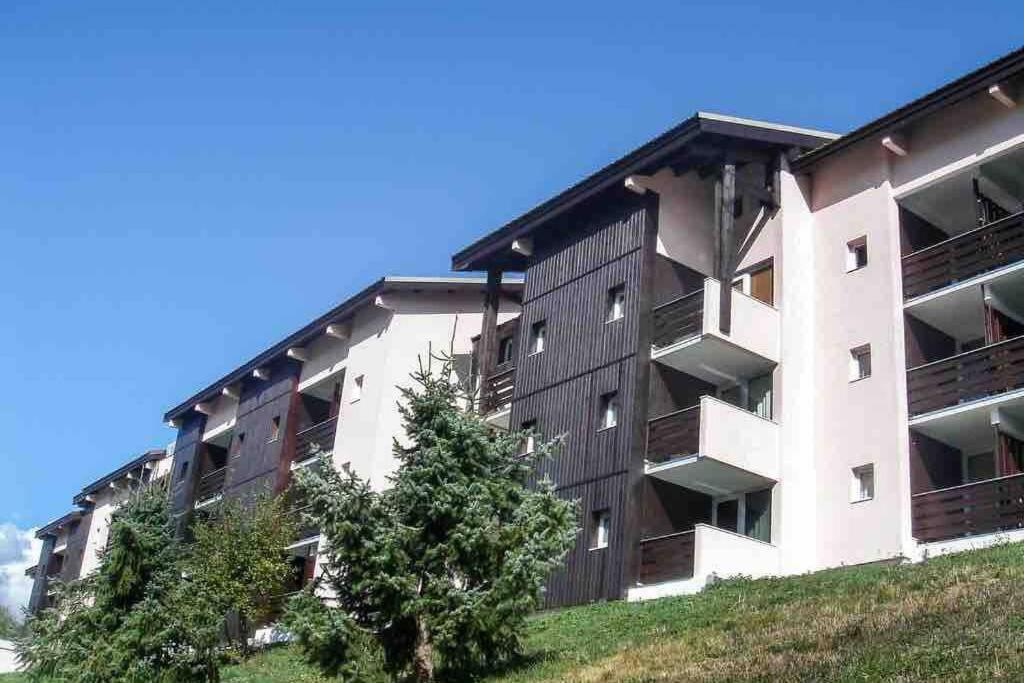 un immeuble d'appartements avec un arbre devant dans l'établissement Petit appartement Labellisé Les 2 Alpes résidence Arc en Ciel télésiège Petite Aiguille, à Les Deux Alpes
