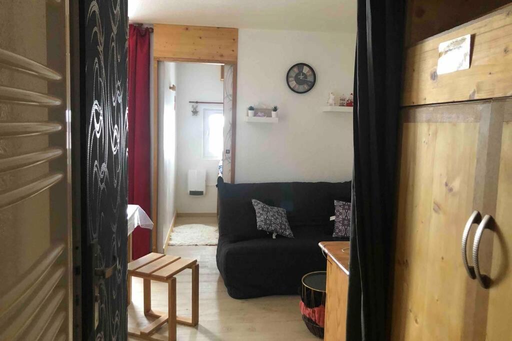 un salon avec un canapé et une horloge au mur dans l'établissement Petit appartement Labellisé Les 2 Alpes résidence Arc en Ciel télésiège Petite Aiguille, à Les Deux Alpes