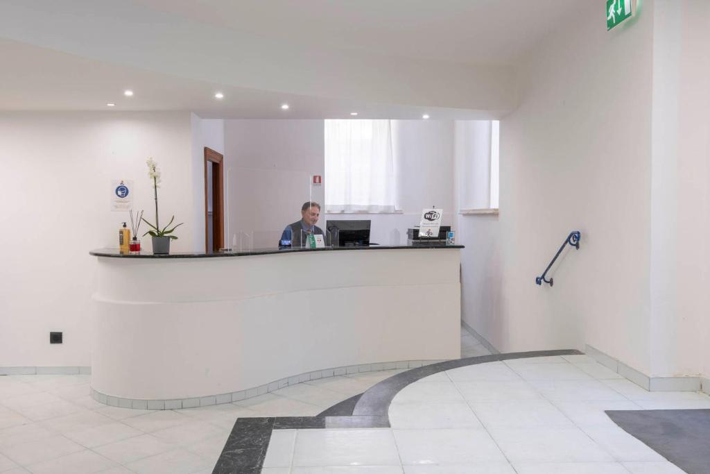 un homme assis à un comptoir dans une pièce dans l'établissement Hotel Del Sole, à Santa Marinella