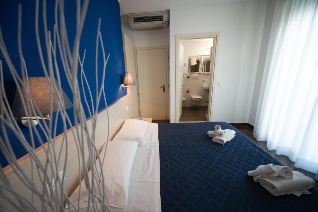 une chambre avec un lit bleu avec des serviettes dessus dans l'établissement Hotel Alabama, à Riccione