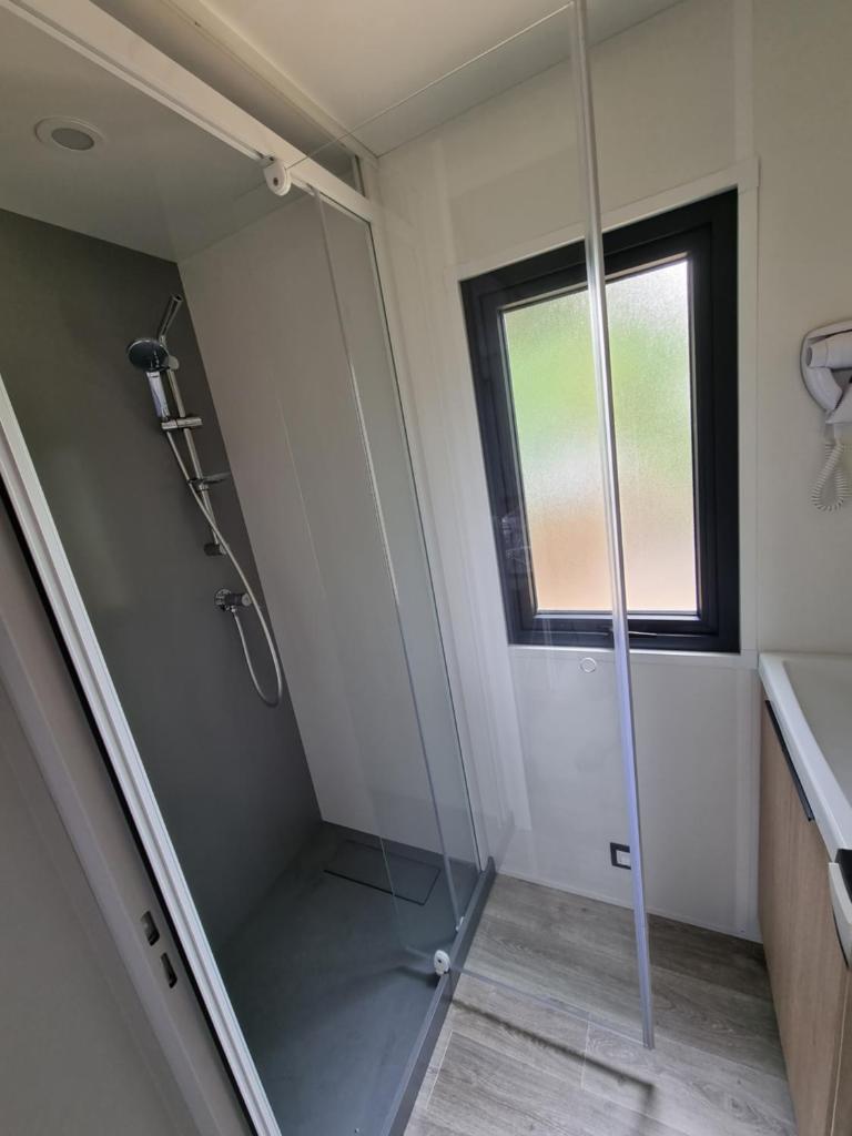 La salle de bains est pourvue d'une douche à l'italienne et d'une porte en verre. dans l'établissement Mobil Home XXL2 4 chambres - Camping Bordeaux Lac, à Bruges 20 autres photos