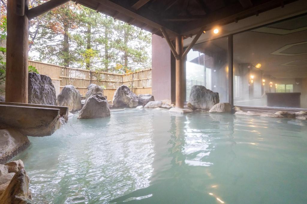 - une piscine avec des rochers dans un parc aquatique dans l'établissement Hotel Sakurai, à Kusatsu