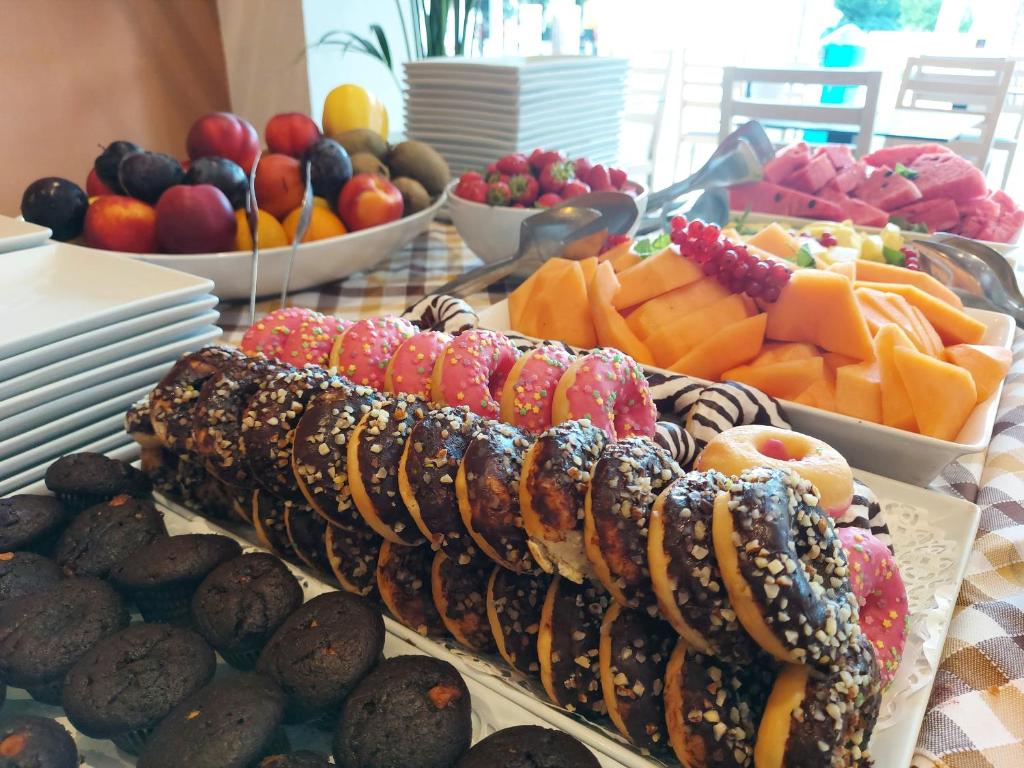 une table recouverte de assiettes de nourriture et de bols de fruits dans l'établissement Hotel Piccadilly, à Lido di Jesolo