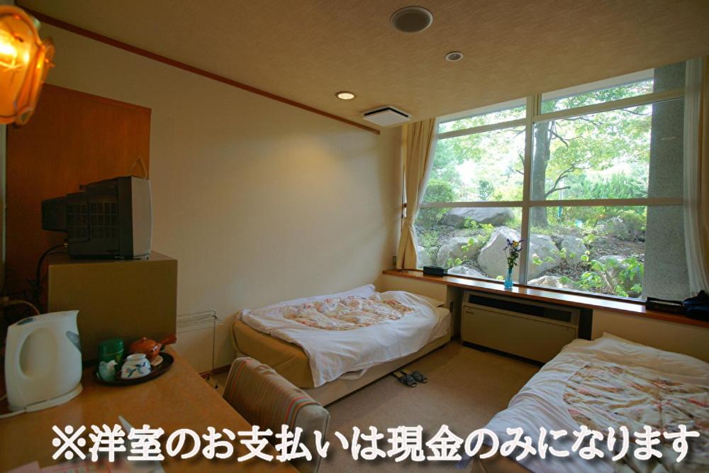 Cette chambre comprend 2 lits et une fenêtre. dans l'établissement Hotel Kaminoyu Onsen, à Kai 37 autres photos