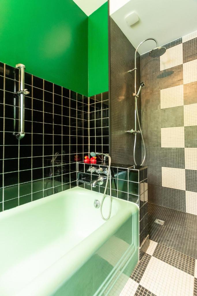 La salle de bains est pourvue d'une baignoire et d'un mur vert. dans l'établissement GITE Du MISFON "VINTAGE 70', à Bazouges-sur-le-Loir