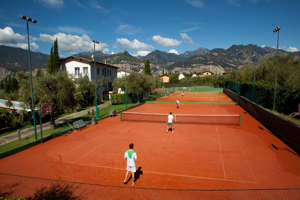 trois personnes jouant au tennis sur un court de tennis dans l'établissement Club Hotel Olivi - Tennis Center, à Malcesine