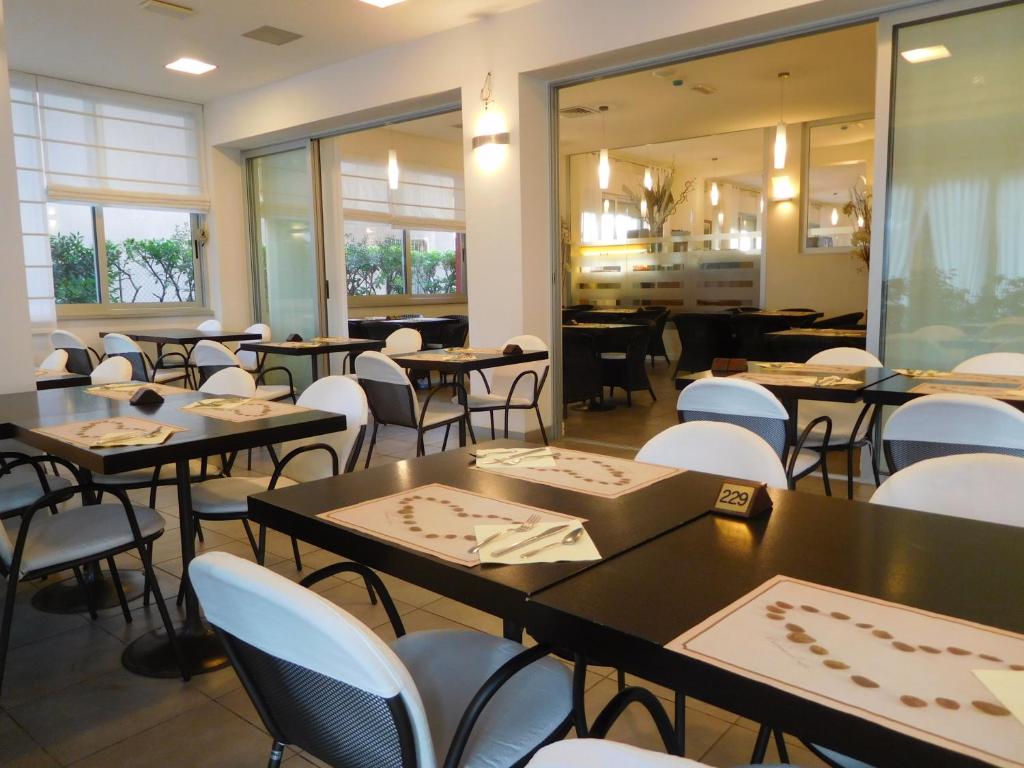 une salle à manger avec des tables et des chaises blanches dans l'établissement Hotel Emperador, à Lido di Jesolo