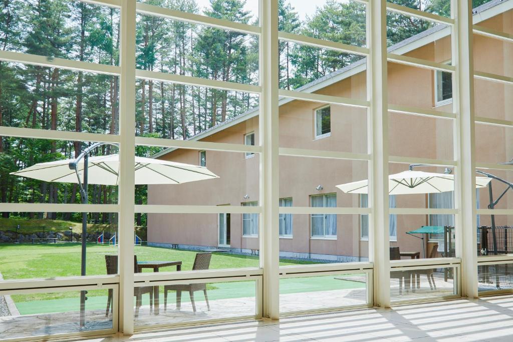 - une vue depuis les fenêtres d'un bâtiment avec des tables et des parasols dans l'établissement Yutorelo Tateshina Hotel with DOGS, à Chino