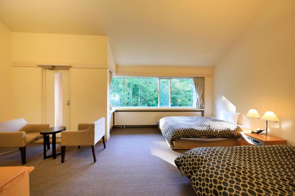 une chambre d'hôtel avec deux lits et une fenêtre dans l'établissement Yutorelo Tateshina Hotel with DOGS, à Chino 37 autres photos
