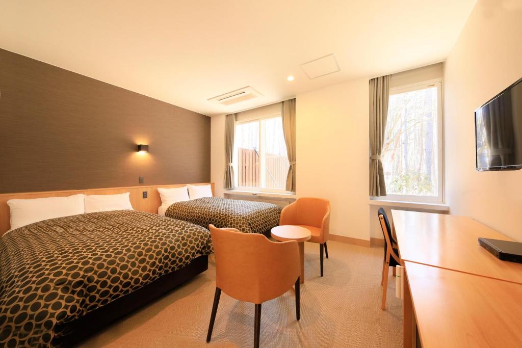 une chambre d'hôtel avec deux lits et un bureau dans l'établissement Yutorelo Tateshina Hotel with DOGS, à Chino