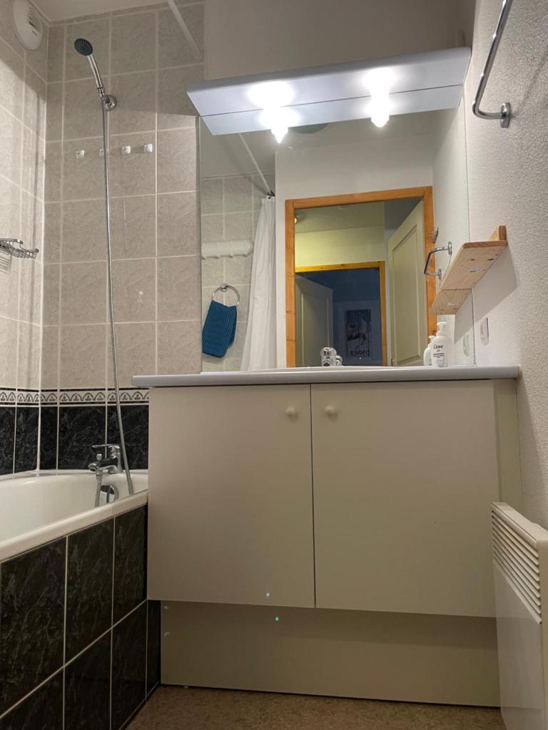 une salle de bain avec un lavabo, une baignoire et un miroir dans l'établissement Le ValmySki, à Valmeinier