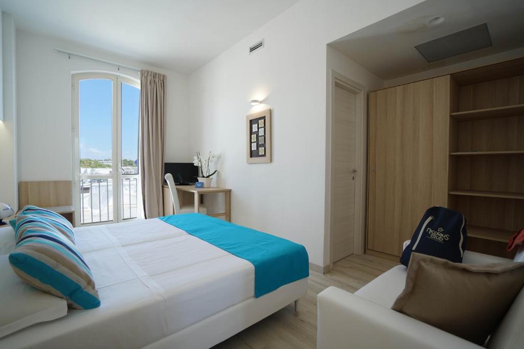 une chambre avec un lit, un canapé et une fenêtre dans l'établissement Nicolaus Prime Il Gabbiano Hotel, à Pulsano