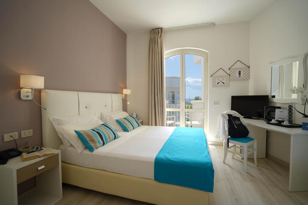 une chambre avec un lit, un bureau et une fenêtre dans l'établissement Nicolaus Prime Il Gabbiano Hotel, à Pulsano