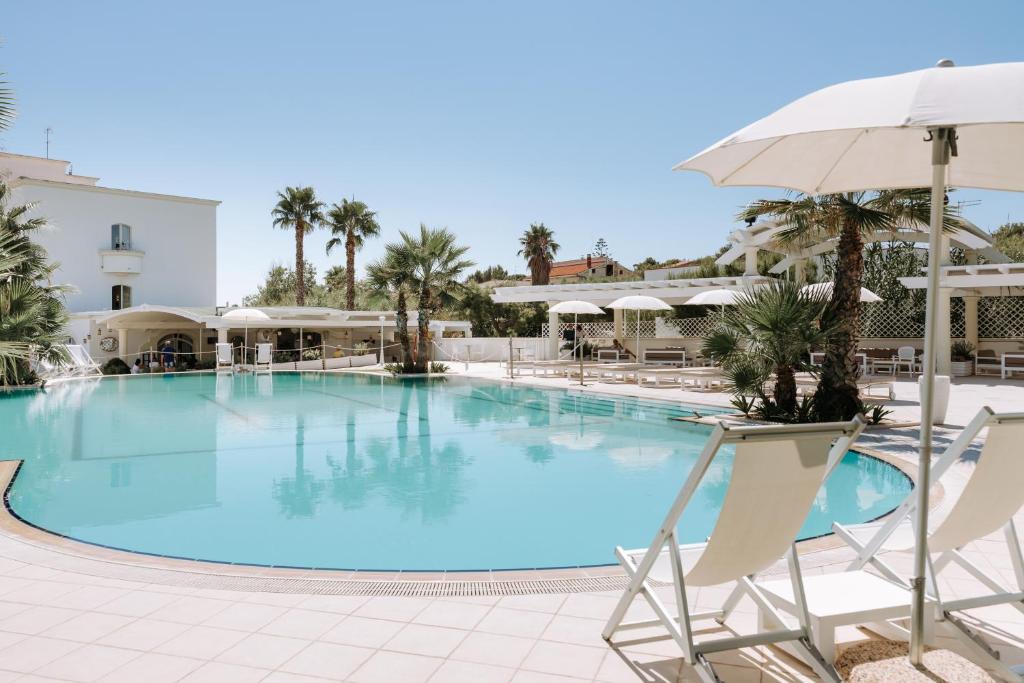 une grande piscine avec des chaises et un parasol dans l'établissement Nicolaus Prime Il Gabbiano Hotel, à Pulsano