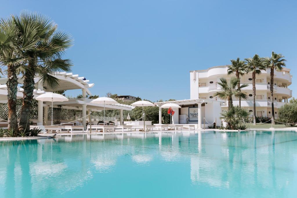 une piscine avec des palmiers en face d'un hôtel dans l'établissement Nicolaus Prime Il Gabbiano Hotel, à Pulsano 99 autres photos