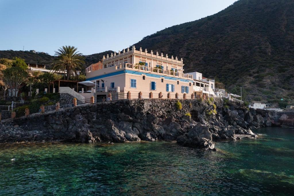 une maison sur une falaise au bord de l'eau dans l'établissement Hotel L'Ariana ISOLE EOLIE - UNA Esperienze, à Leni