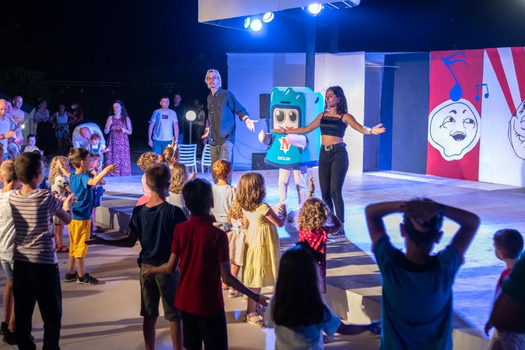un groupe d’enfants regardant un artiste sur une scène dans l'établissement Nicolaus Club La Giurlita, à Ugento 57 autres photos