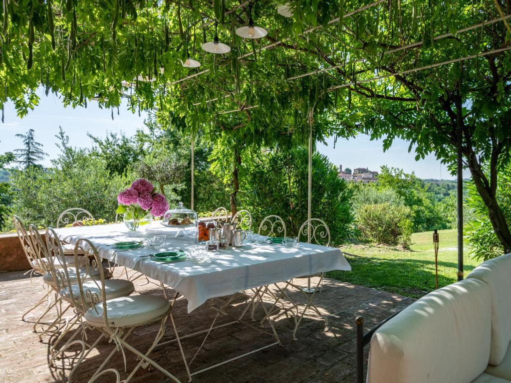 une table avec une nappe et des chaises blanches sous un arbre dans l'établissement Villa Bric del Vento by Interhome, à Soglio