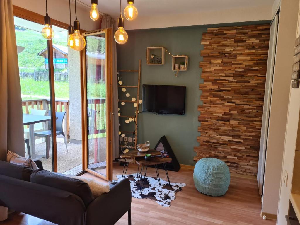 un salon avec un canapé et un mur de briques dans l'établissement LES ORRES 1800 Appartement 4 p JACUZZI balnéo privé Vue piste piscine résidence, aux Orres