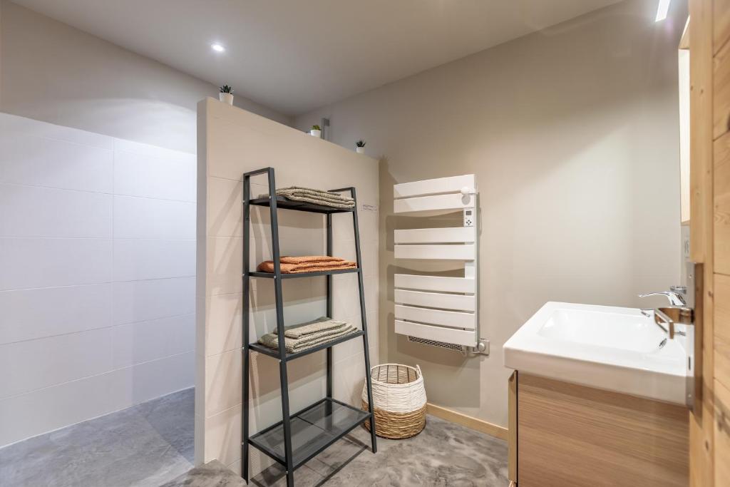 une salle de bain avec un lavabo et une étagère avec des serviettes dans l'établissement Bourg Saint Maurice Centre 45m2 prox Gare SNCF et Funiculaire, à Bourg-Saint-Maurice
