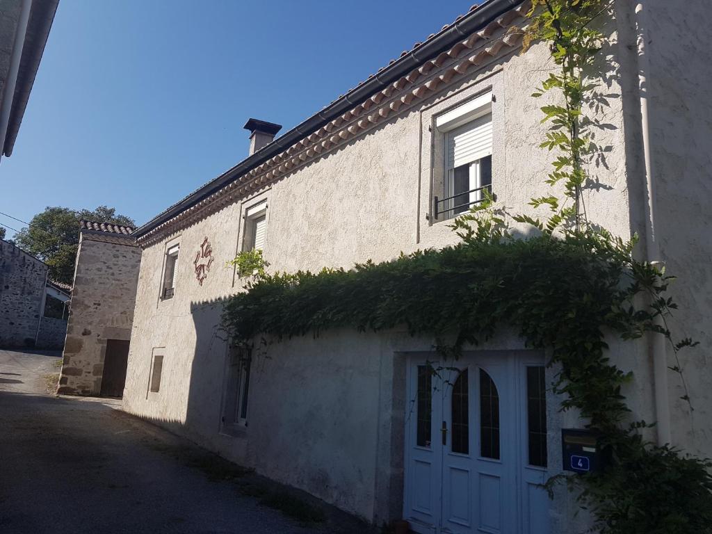 - un bâtiment en briques blanches avec un garage blanc dans l'établissement gite a la campagne, à Noailhac