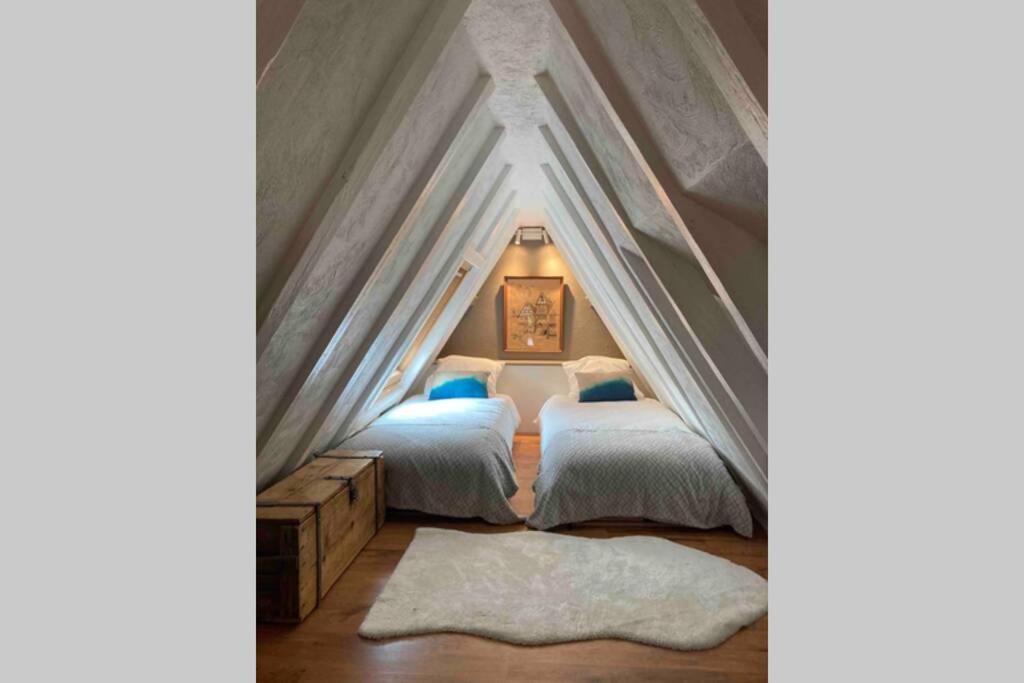 une chambre avec deux lits dans un grenier dans l'établissement Le Clos d’Azel - Le gîte du cocher avec piscine, à Flexbourg