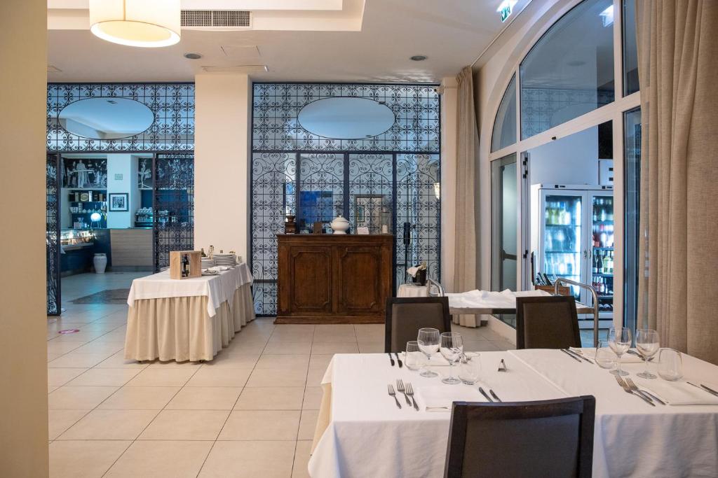 un restaurant avec des tables et des chaises blanches et une fenêtre dans l'établissement Club Azzurro Hotel & Resort, à Porto Cesareo