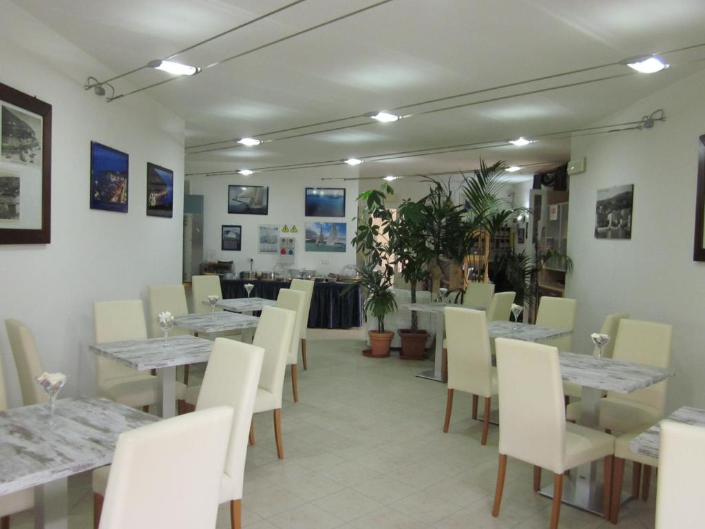une salle à manger avec des tables blanches et des chaises blanches dans l'établissement Hotel Villa Smeraldo, à Orbetello