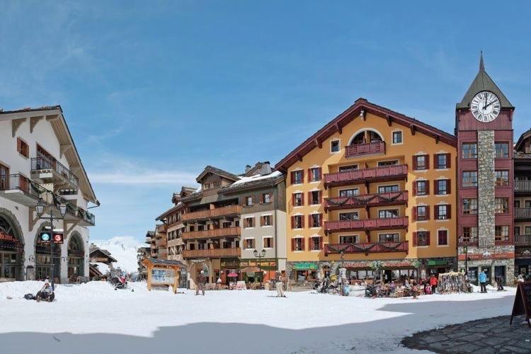 un groupe de bâtiments avec une tour d'horloge dans l'établissement ARC 1950 Appartement de Standing rénové avec vue sur le Mont Blanc - Paradiski 5 Cristaux, à Arc 1950