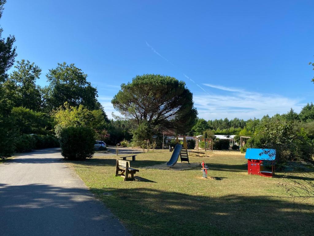 - un parc avec une aire de jeux dotée de bancs et d'un toboggan dans l'établissement Mobilehome 3 chambres curistes camping piscine, à Saint-Paul-lès-Dax