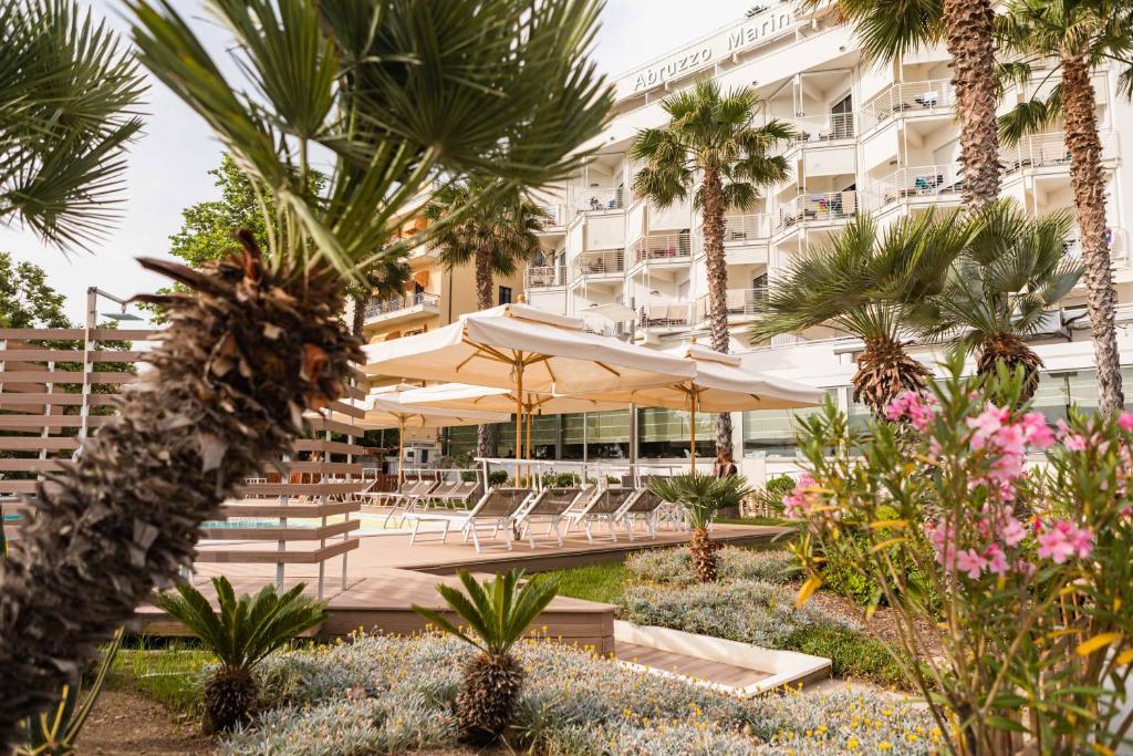 un hôtel avec des tables, des parasols et des palmiers dans l'établissement Hotel Abruzzo Marina, à Silvi Marina