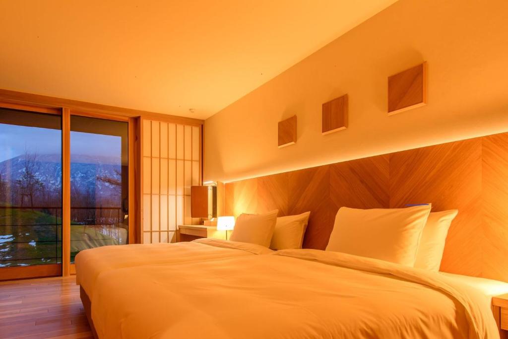 une chambre avec un grand lit et une grande fenêtre dans l'établissement NISEKO Inn of Youtei Raku Suisan, à Kutchan