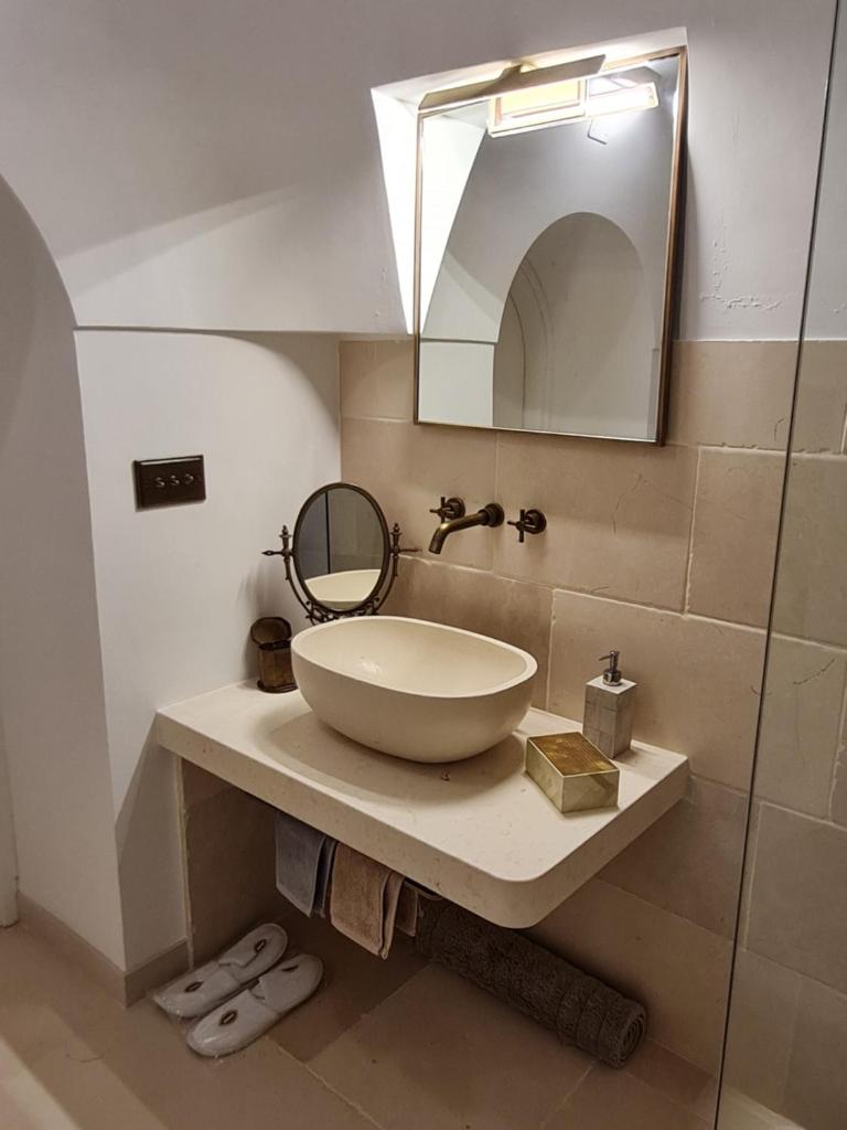 une salle de bain avec un lavabo et un miroir dans l'établissement Trulli Martina, à Martina Franca