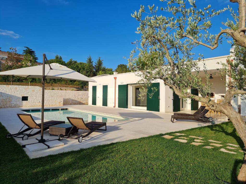une cour avec une piscine, 2 chaises et un parasol dans l'établissement Trulli Martina, à Martina Franca