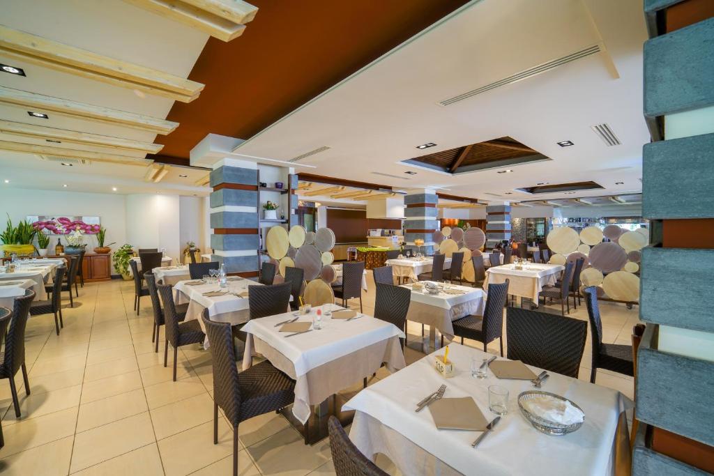 une salle à manger avec des tables et des chaises blanches dans l'établissement Hotel Residence Sciaron, à Capo Vaticano