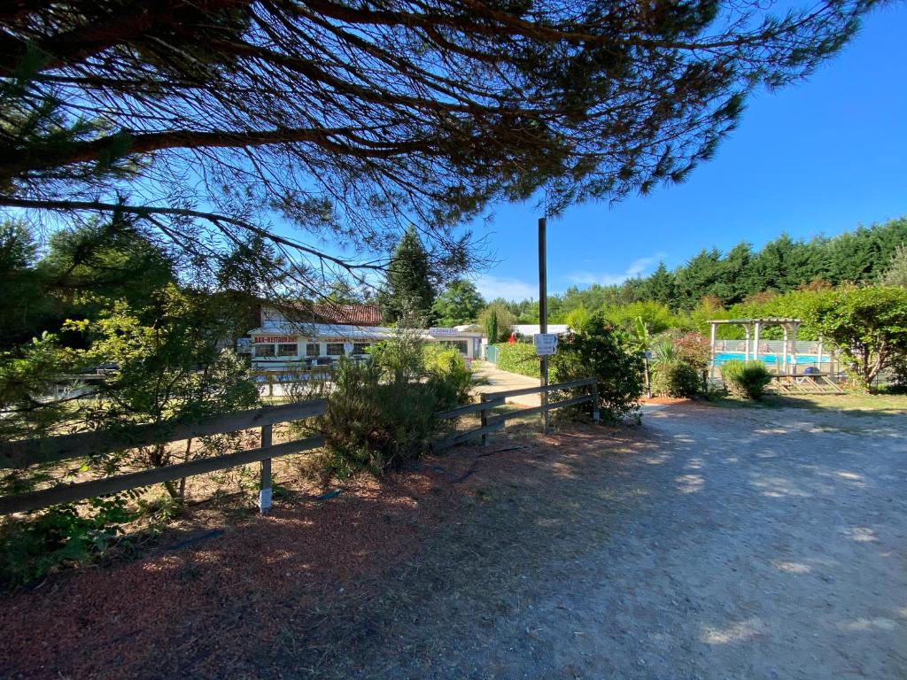une clôture devant une maison arborée dans l'établissement Mobile Home Zen pour 4 à 6 pers camping 4* Saint Paul Les Dax, à Saint-Paul-lès-Dax